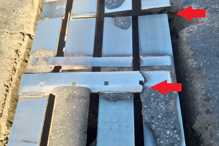 Grelha de um dos bueiros, com destaque para barra transversal rompida e pontas elevadas de duas barras longitudinais