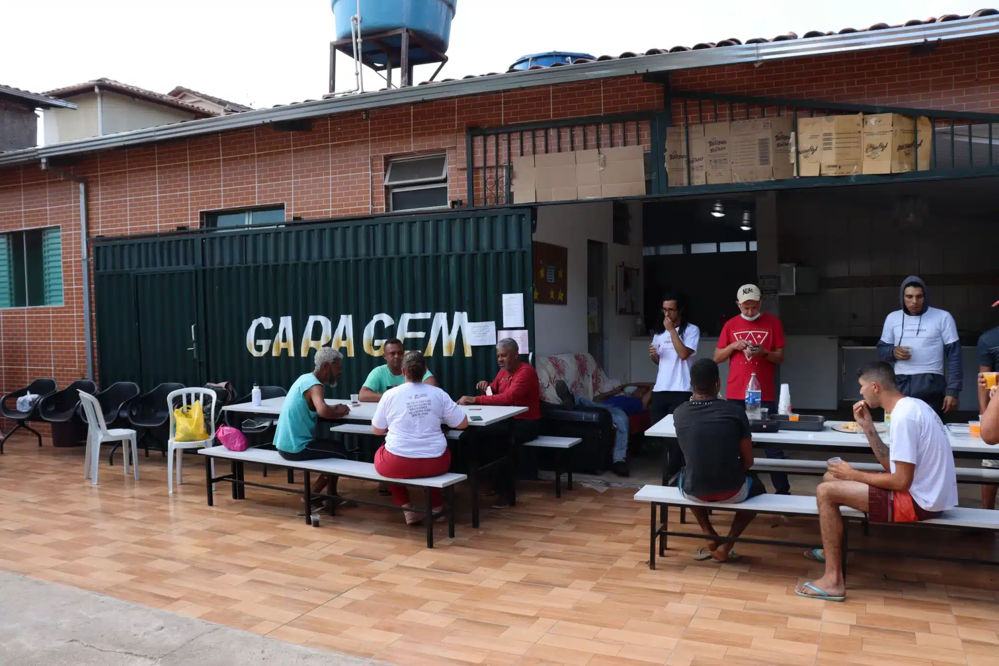 Pátio do Centro POP, em mariana, Minas Gerais. Pessoas em situação de rua assentadas diante de mesas de jogos, em dia de atividades da Semana da Visibilidade de Pessoas em Situação de Rua
