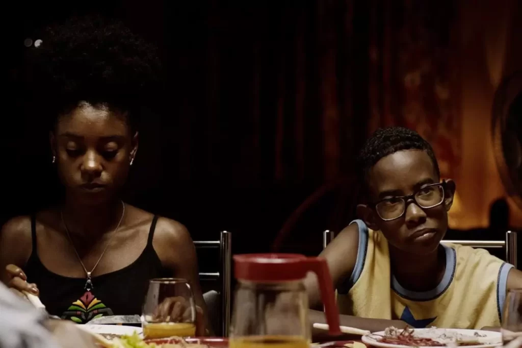 Uma garota e um garoto, ambos jovens, sentados à mesa, em cena do filme Marte Um