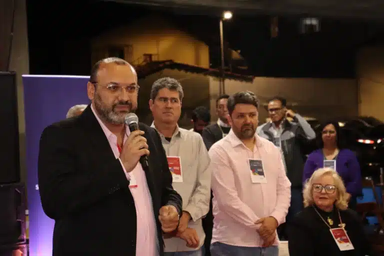 Na abertura da 2ª Semana de Desenvolvimento Econômico de Mariana, representante do Governo de Minas Gerais, fala ao microfone sobre a parceria que será implantada, observado por outras autoridades, de pé, ao fundo