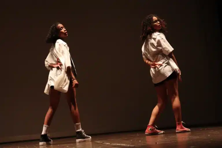 Duas dançarinas, de costas,usando shorts e camisas brancas, apresentando-se na abertura da 6ª edição do Festeco