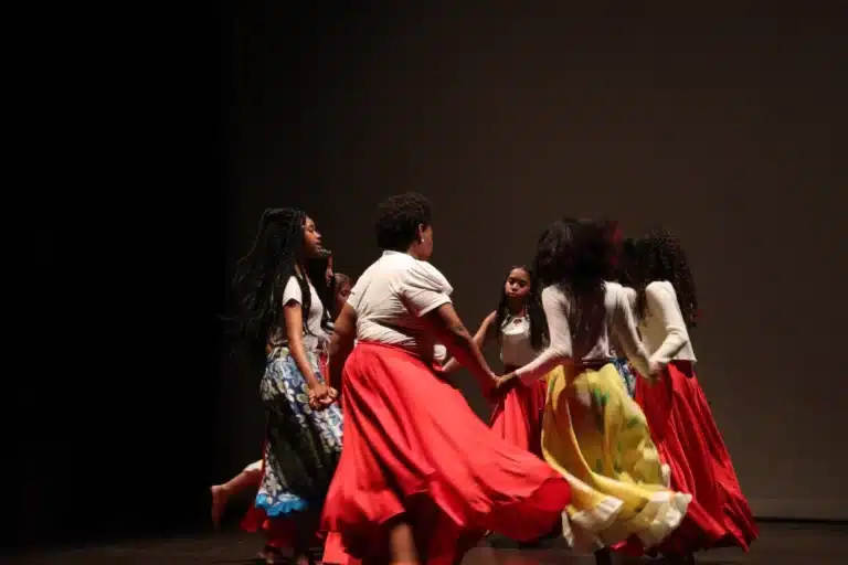 Dançarinas, com roupas coloridas, fazem roda no palco, durante apresentação na noite de abertura do Festeco