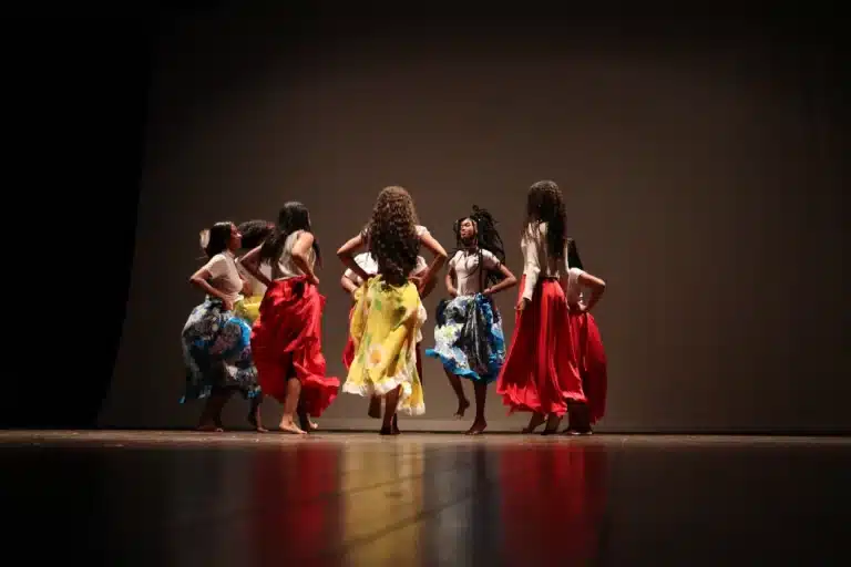 Usando roupas coloridas, 8 meninas se apresentação na noite de abertura da 6ª edição do Festeco, rodopiando com as mãos na cintura