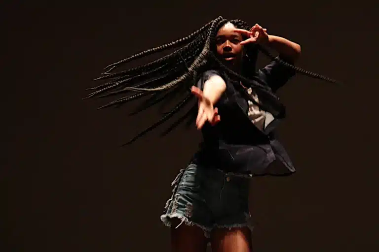 Dançarina, usando short jeans, blusa preta, e com grandes tranças, faz apresentação solo na noite de abertura da 6ª edição do Festeco