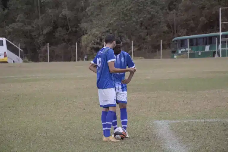 Jogadores do São Caetanense, com camisas azuis e calções brancos, combinam jogada em batida de falta na lateral da área. A equipe ainda briga por classificação no Grupo A.