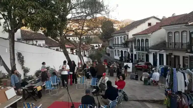 Em primeiro plano, roda de conversa sobre temáticas diversas sobre cultura latino-americana. Ao fundo, exposições de quadros, pinturas e venda de produtos alimentícios