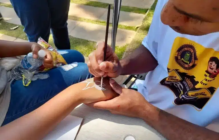 Mão de uma criança sendo pintada com temática de flores, durante a Ação Transitolândia
