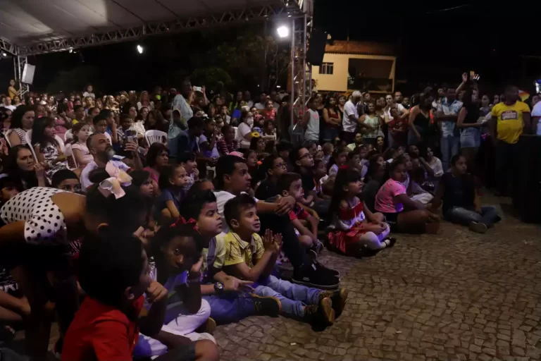 Crianças sentadas no chão e muitas pessoas prestigiando a abertura do Encontro Internacional de Palhaços
