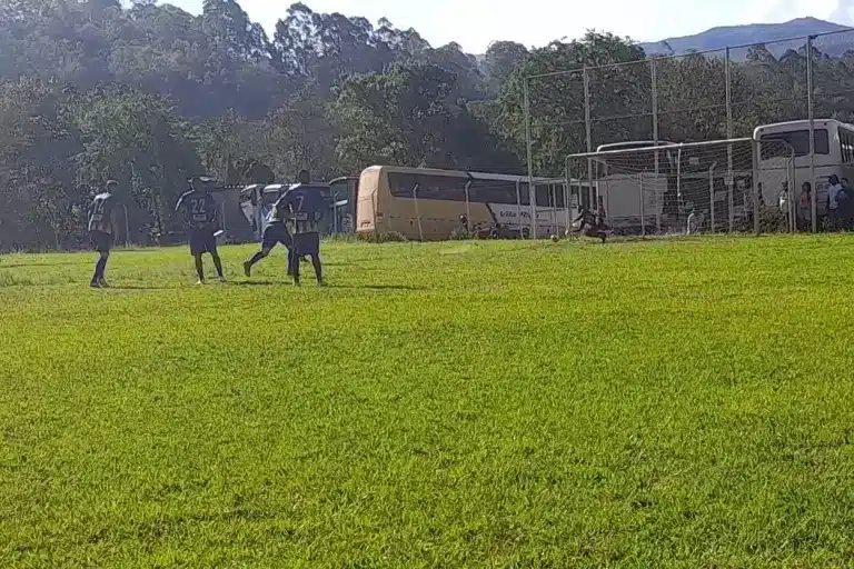 Jogadores observam batida de pênalti. Ao fundo, goleiro cai para o canto direito, mas não consegue fazer a defesa.