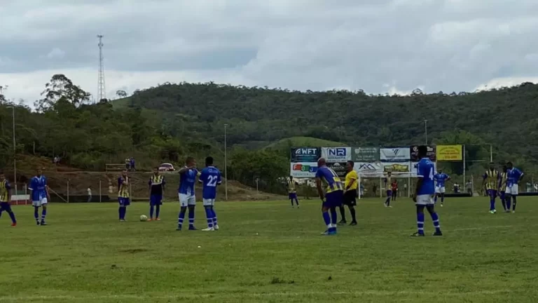 Jogadores de azul e branco se cumprimentam, enquanto os adversários se preparam para a saída de bola.