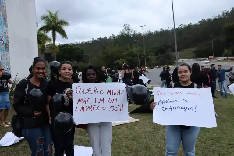 Profissionais de Enfermagem portam cartazes onde se lê: "Quero minha mãe em um emprego só!!" e "Não somos heróis. Apoiem a Enfermagem!"