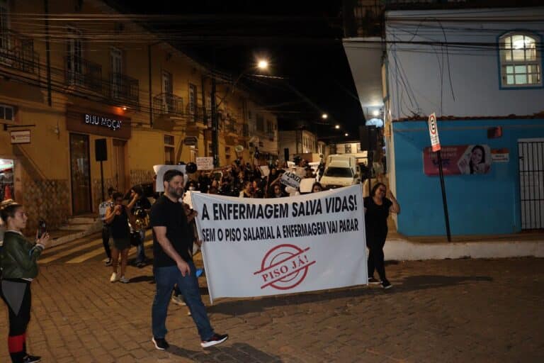 Passeata passa plea esquina das ruas Zizinha Camelo e 16 de julho, com Mauro Luiz Fonseca, presidente da ASSENF á frente, em primeiro plano, ao lado de faixa onde se lê: "A Enfermagem salva vidas! Sem piso salarial, a Enfermagem vai parar. Piso já"