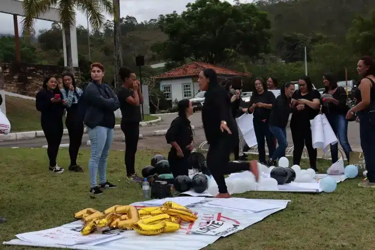 manifestantes da Enfermagem, confeccionando cartazes na concentração da passeata, no gramado do pátio do Terminal Rodoviário de Mariana