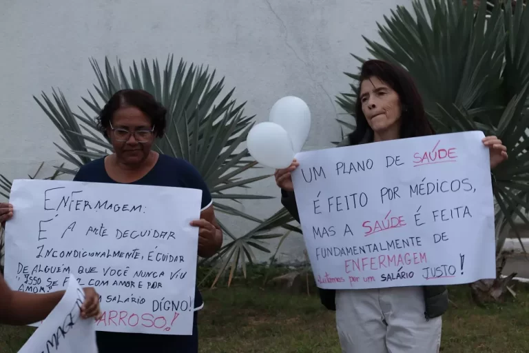 Manifestantes portando cartazes, antes da passeata dos profissionais de Enfermagem.