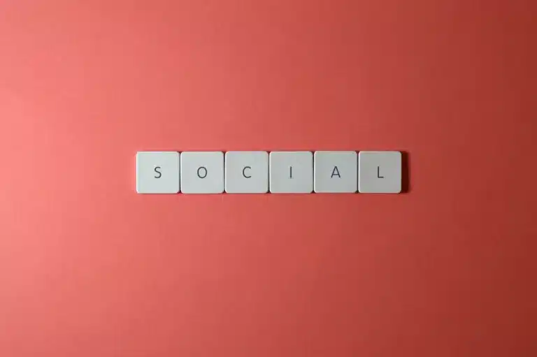 Sobre fundo avermelhado, quadradinhos de madeira, com letras, forma a palavra "Social"