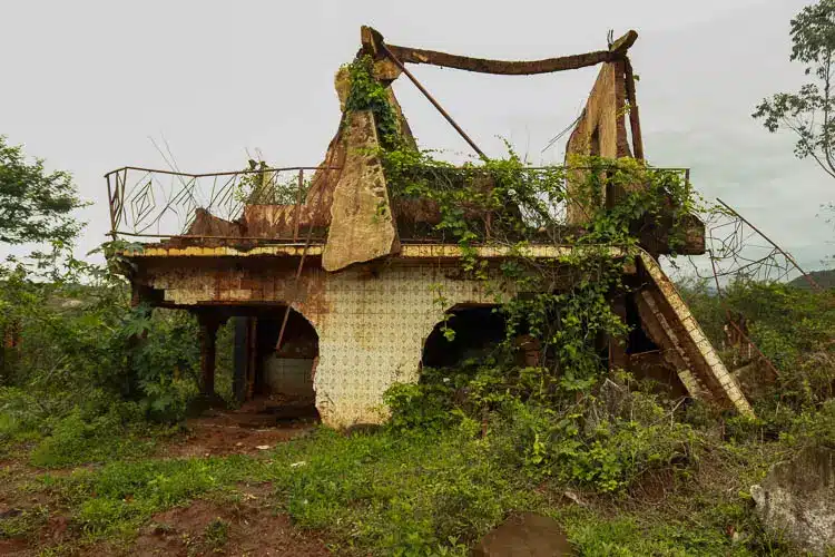 Uma das casas de Bento Rodrigues, distrito marianense de Bento Rodrigues, completamente destruída pela lama proveniente do rompimento da barragem de Fundão, em registro de novembro de 2017, com vegetação encobrindo parte do que sobrou da edificação