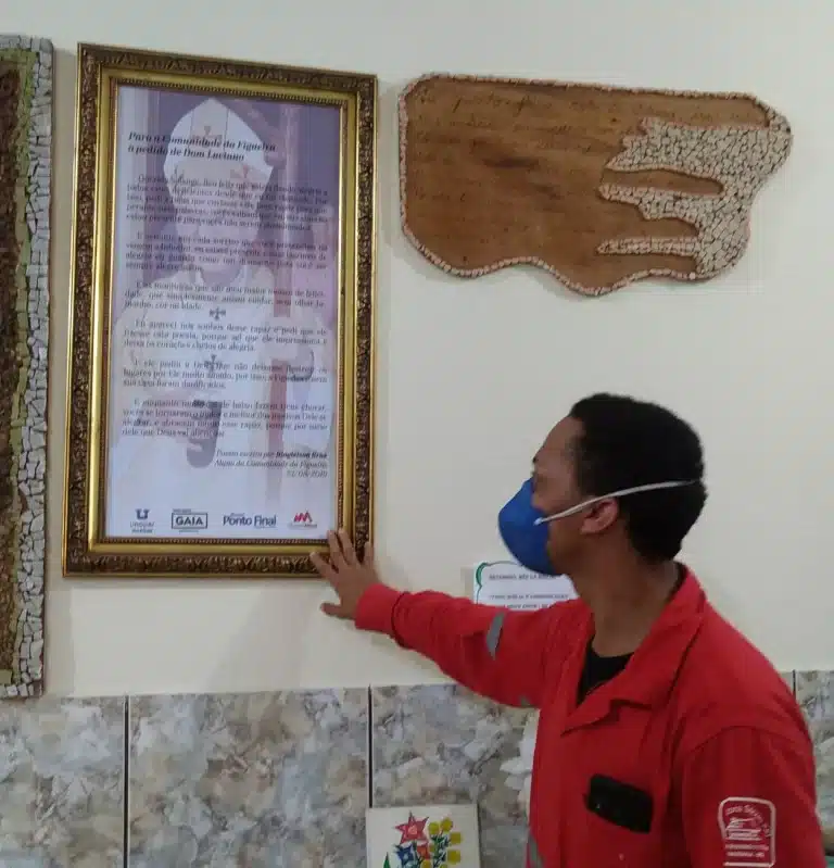 Diogleison Brás José, que passou de usuário a funcionário da Comunidade da Figueira, olha o retrato de Dom Luciano