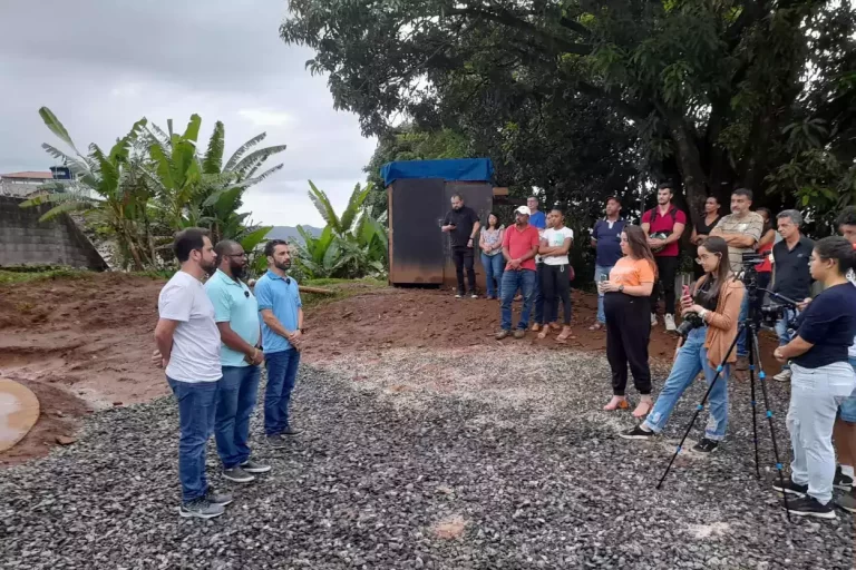 Presidente da Câmara Municipal, Prefeito Interino e Diretor do SAAE, em cerimônia de entrega de reservatórios no bairro Rosário, observados por assistentes e pessoas que fazem fotos e gravação de vídeo