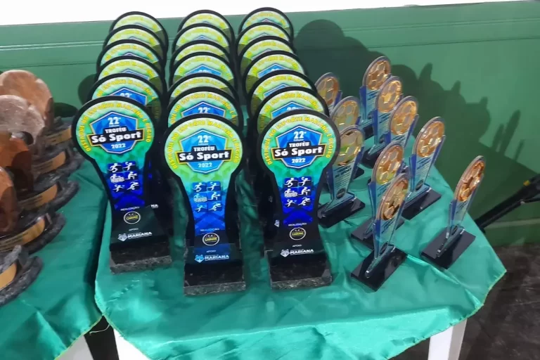 Troféus Só Sport, sobre mesa coberta com toalha verde.