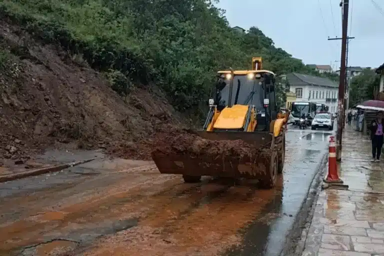 Pá carregadeira da Secretaria de Obras retira material de deslizamento de encosta sobre viapública em Ouro Preto
