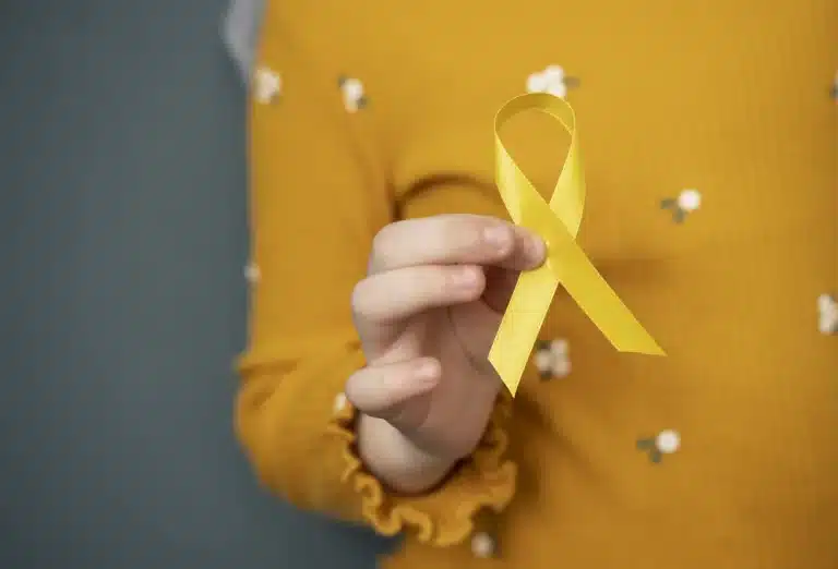 Mão de mulher segurando laço amarelo, simbolo da campanha Setembro Amarelo