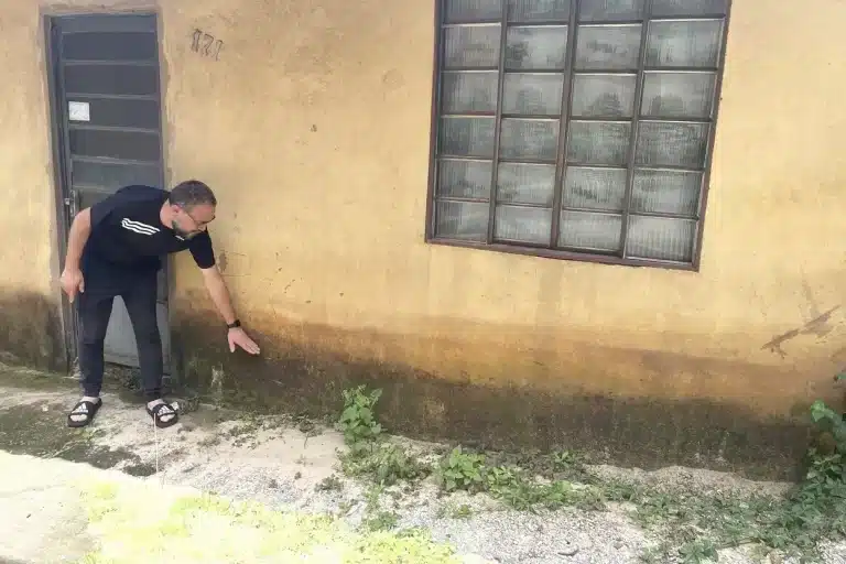 Morador de Passagem de Mariana, indica o nível atingido, na fachada da casa, pelas águas de chuva