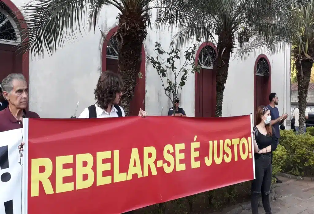 Manifestantes protestam conta a Senouro, portando faixa com os dizeres: "Rebelar-se é justo!"