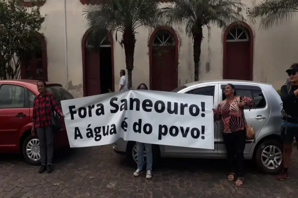 Manifestantes portam faixa pedindo a suspensão da concessão da Saneouro, diante da Prefeitura de Ouro Preto
