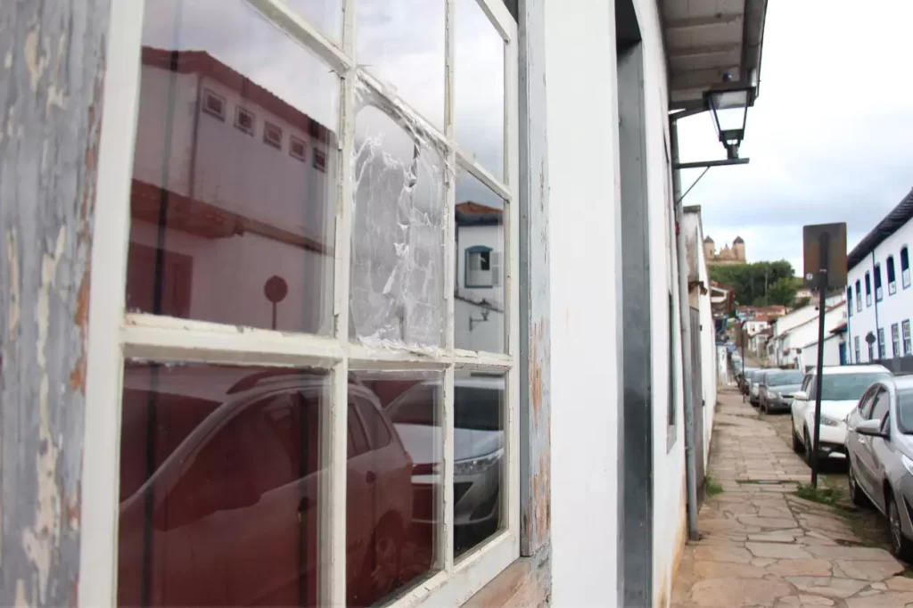 Fachada do prédio da biblioteca, destacando a proteção com plástico colocada em lugar do vidro quebrado em uma janela