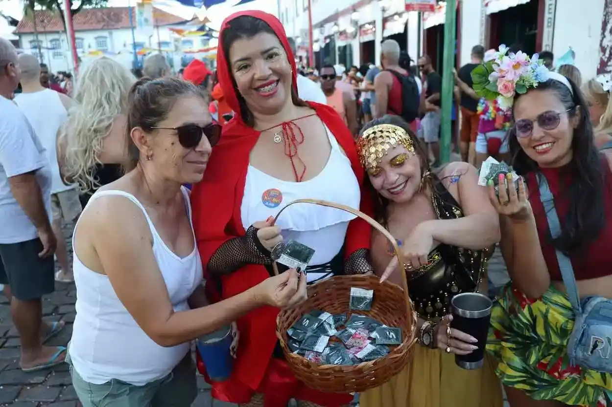 Fantasiada de Chapeuzinho Vermelho, foliã usa a cestinha para distribuir camisinhas no desfile da Banda dos Farrapos
