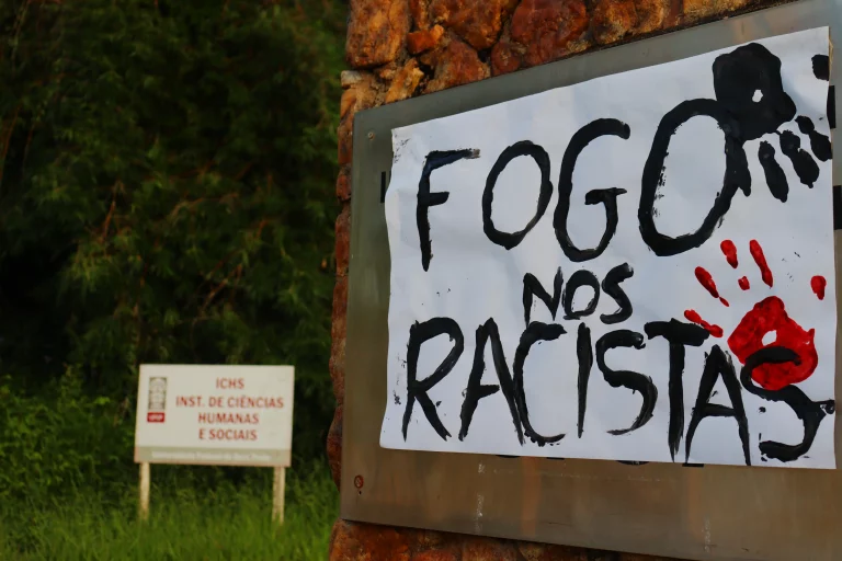 Na entrada do ICHS, sobre a placa do campus, foi pregada a expressão "Fogo nos racistas", em forma de protesto. – Foto: Gustavo Batista/Agência Primaz