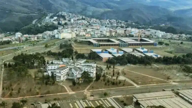 Vista aérea do campus da Universidade Federal de Ouro Preto (UFOP), com prédios acadêmicos, residenciais e a cidade ao fundo cercada por montanhas.