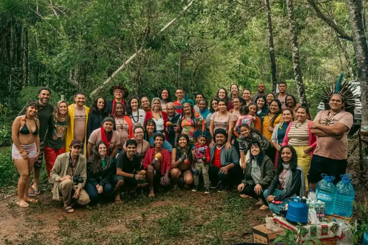 Um grupo de indigenas posa para fotografia em uma mata.