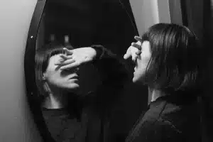 Mulher, diante do espelho, evita ver seu reflexo