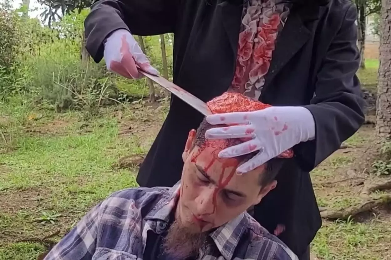 Captura de tela do filme Tropical SOV que mostra a cena de um homem abrindo a cabeça do outro com uma faca.