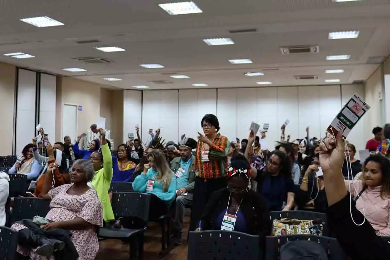 Platéia da II Conferência Municipal de Igualdade Racial levanta os braços durante votação das propostas de cada eixo temático.