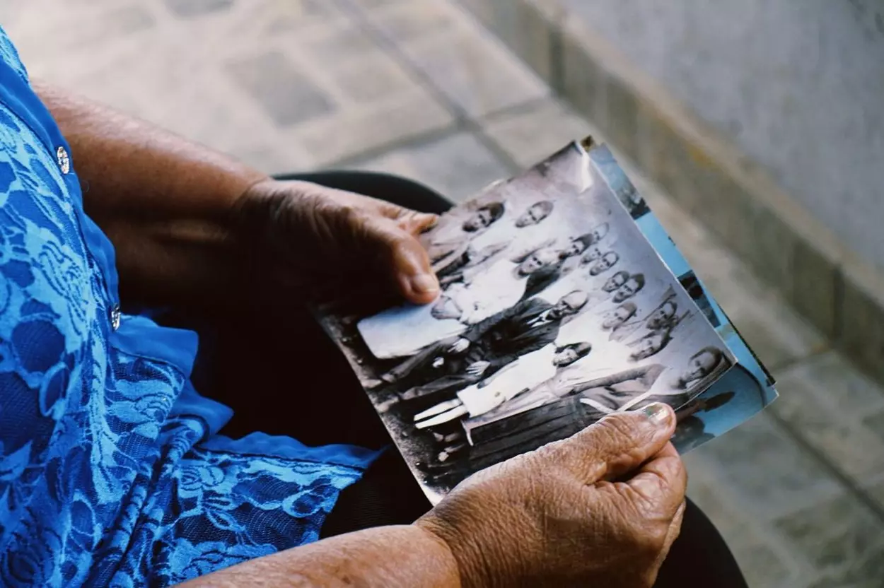 Cena do documentário “Entre Nós” mostra mãos segurando uma antiga fotografia em preto e branco.