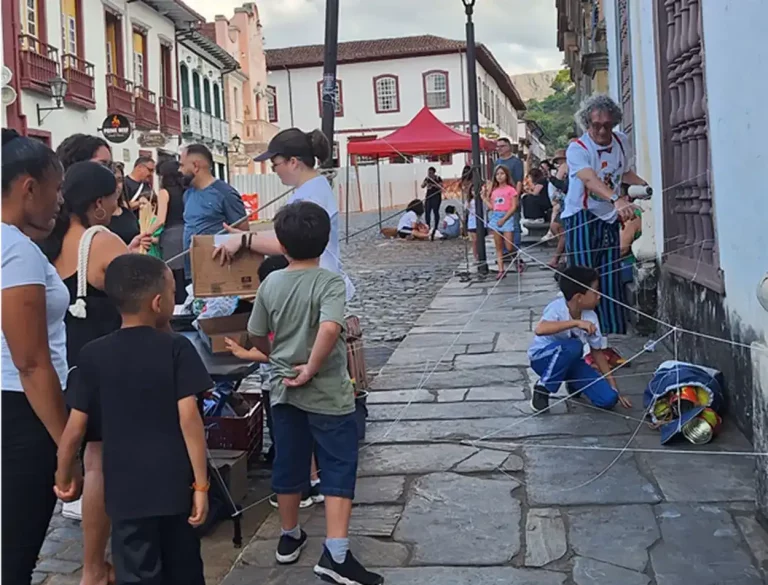 Crianças interagem com fios amarrados na parede em uma brincadeira de rua durante a Semana Mundial do Brincar.