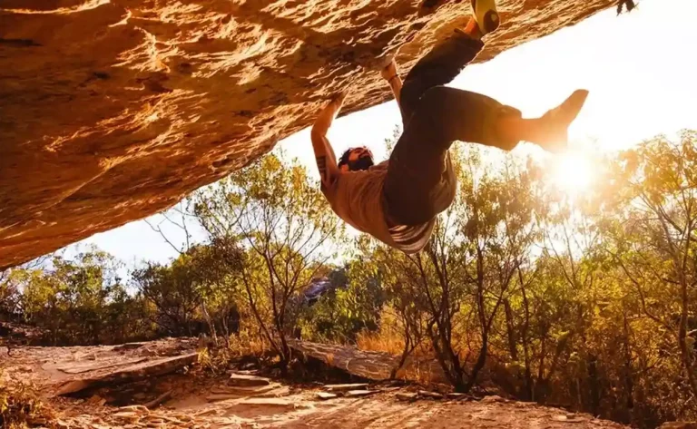 Um homem se segura em uma pedra bem grande enquanto pratica atividades de montanhismo durante abertura da temporada