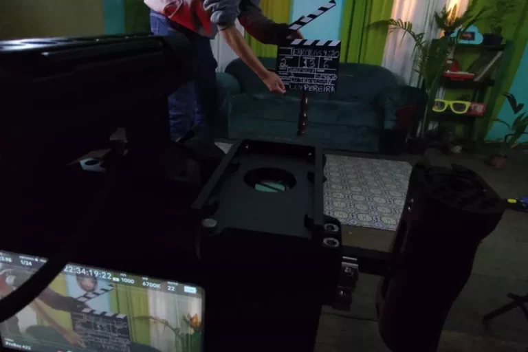 Pessoa segurando claquete de cinema durante gravação em estúdio. Foto para texto sobre capacitação de agentes culturais.