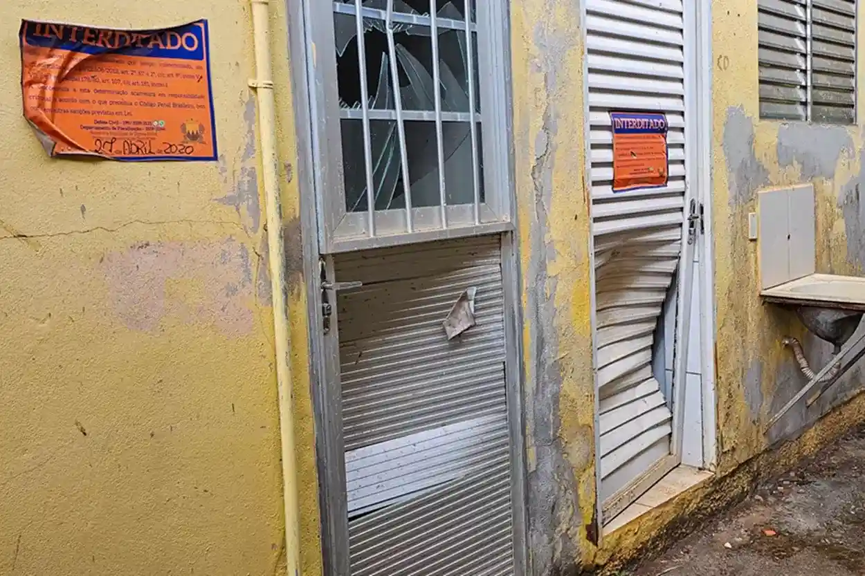 Portas de alumínio e vidro danificadas com sinais de arrombamento em uma casa da área evacuada.