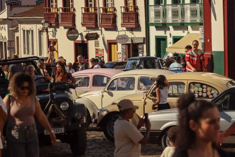 Diversas pessoas e veículos durante encontro de carros antigos em Mariana