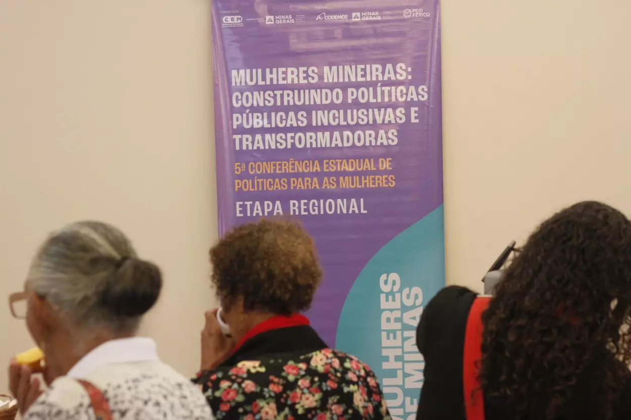 Faixa da conferência exibe o tema “Mulheres mineiras: construindo políticas públicas inclusivas e transformadoras”, reforçando o caráter participativo e plural do evento.