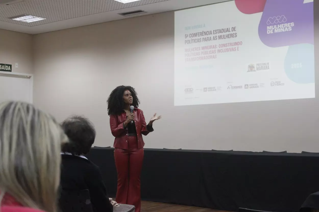 Marciele Delduque fala ao microfone em um auditório durante a etapa regional da 5ª Conferência Estadual de Políticas para as Mulheres