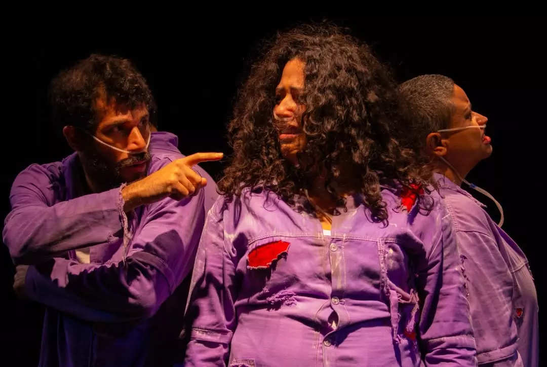 Três atores contracenam no palco durante uma cena dramática do espetáculo Uiraçu.