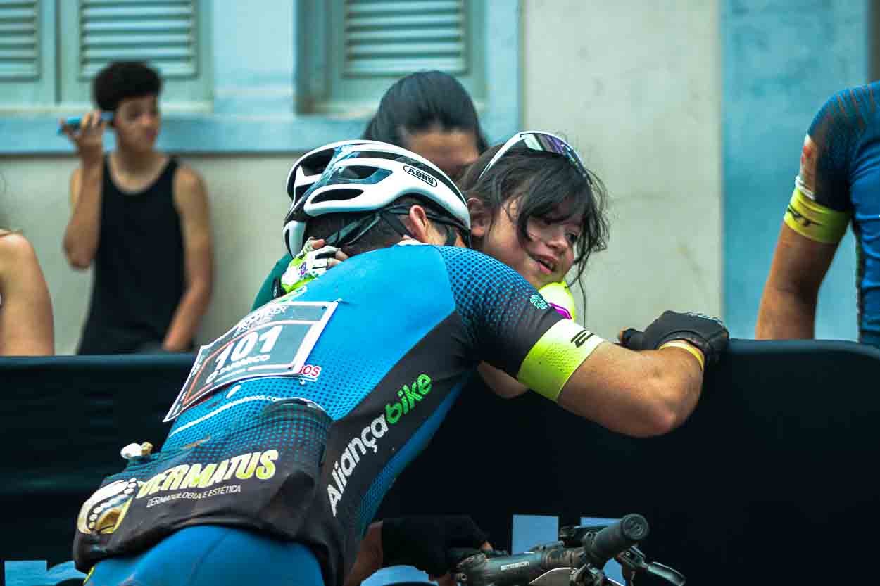 Pai e filha se abraçando após a chegada do Iron Biker