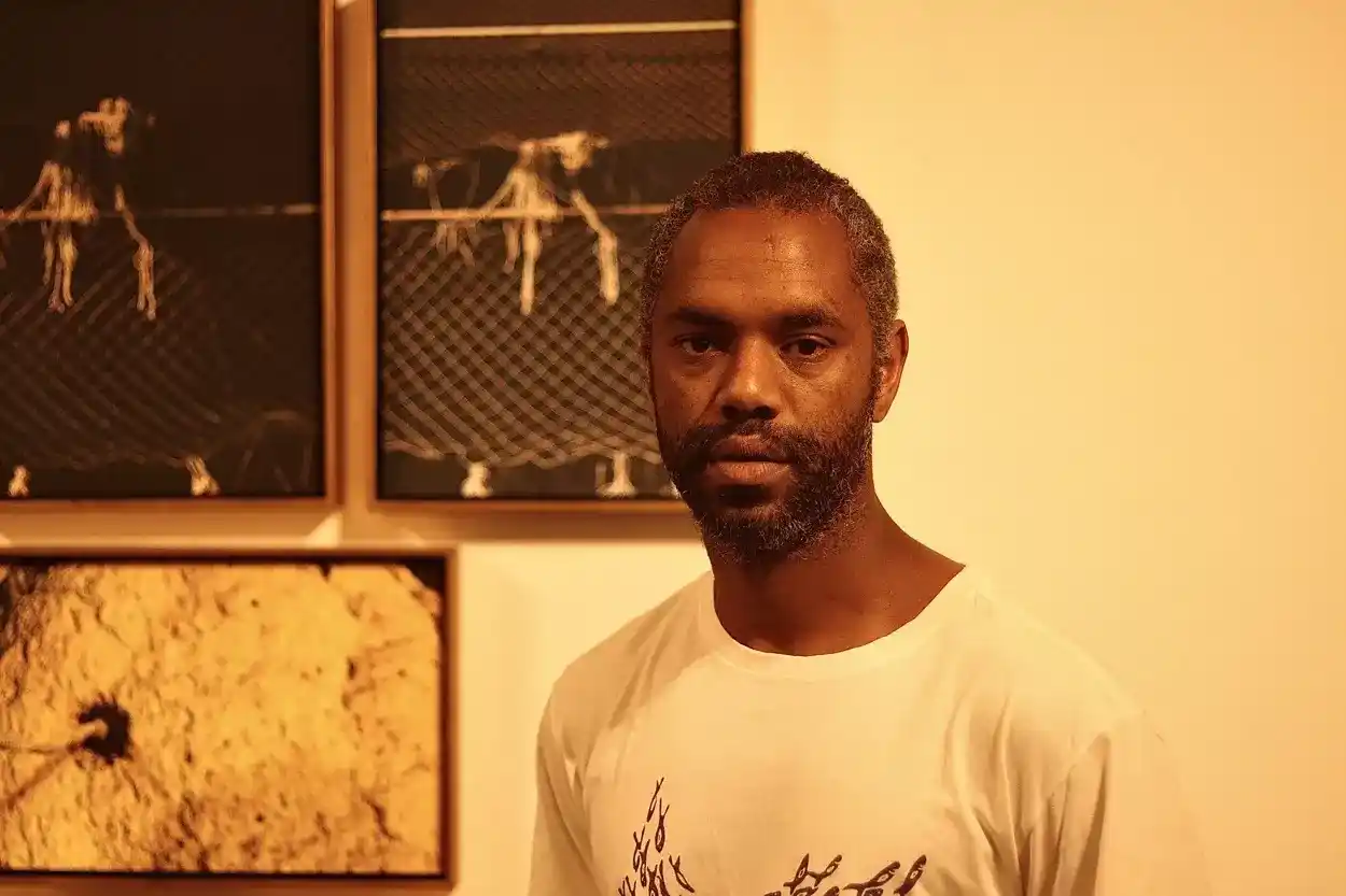 Fotógrafo convidado Alisson Lessa em frente a sua exibição na mostra Desvia, que foca em um desviar atemporal, tendo a câmera como válvula de escape.- Foto: Joyce Campolina/Agência Primaz