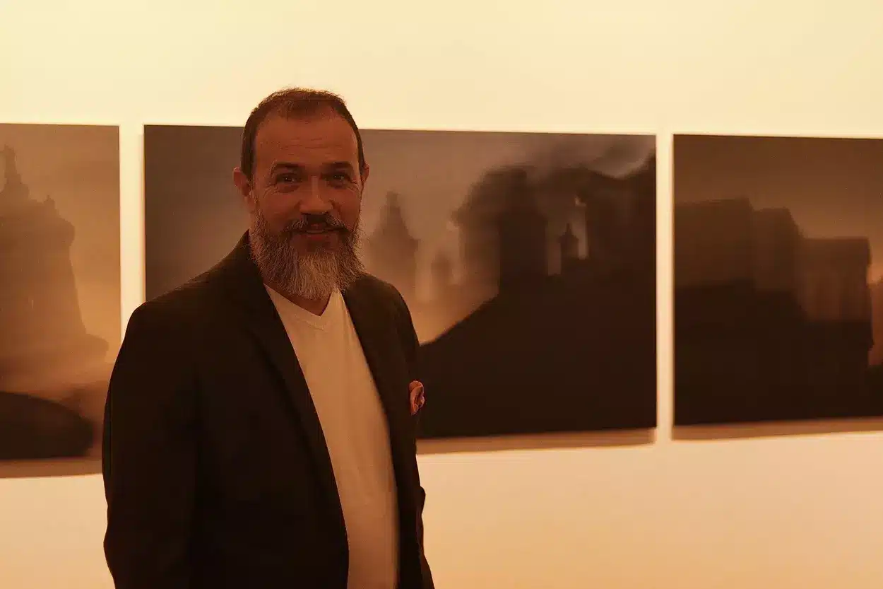 César Tropia em frente ao trabalho exposto na exposiçao DESVIA em Ouro Preto, que segundo o fotógrafo, foi escolhido a dedo lugares de sua preferência na cidade. “busquei lugares da minha preferência, o Rosário, a Escola de Minas e aquela vista do Rosario pra quem está de costas pra igreja, o pico do itacolomi aparece bem entre os telhados e todas tiradas ao pôr do sol, para ter essa silhueta”, explica. - Foto: Joyce Campolina/Agência Primaz