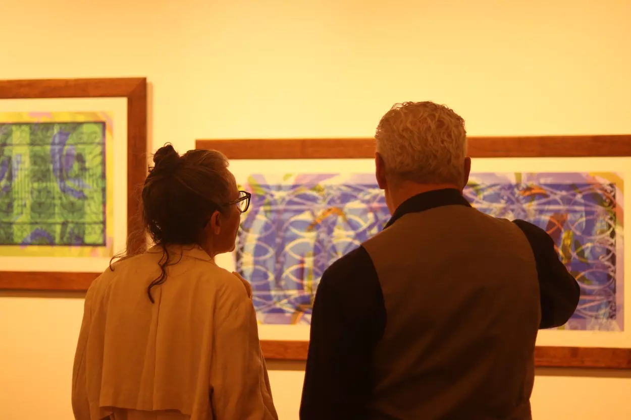 Eduardo Tropia e visitante em frente a sua exibição na exposição DESVIA do Coletivo Olho de Vidro em Ouro Preto, que mescla pela primeira vez no trabalho do fotógrafo, foto e pintura. - Foto: Joyce Campolina/Agência Primaz