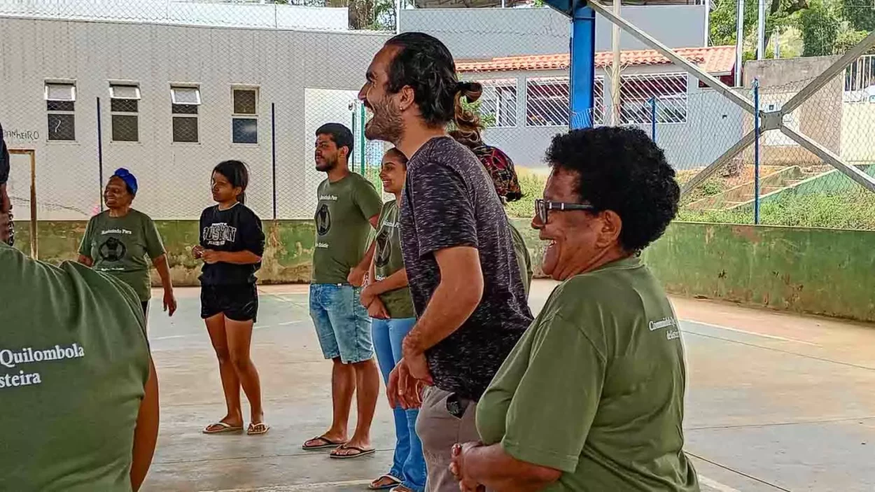 Pessoas em roda fazem atividades teatrais dentro da quadra de Gesteira, a foto destaca o professor do projeto
